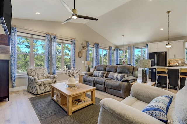 living room with baseboards, light wood finished floors, a healthy amount of sunlight, and vaulted ceiling