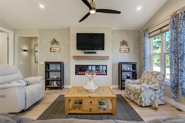 living area featuring visible vents, lofted ceiling, recessed lighting, wood finished floors, and a glass covered fireplace