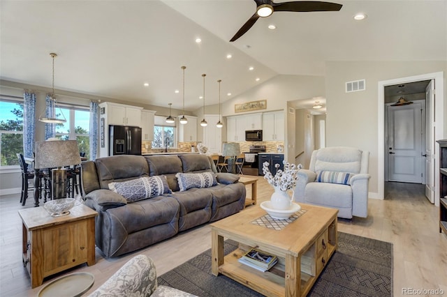 living area with visible vents, baseboards, recessed lighting, light wood-style floors, and high vaulted ceiling