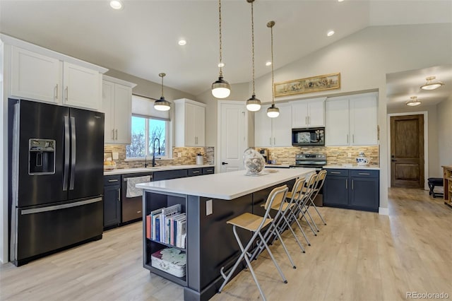 kitchen with black appliances, a center island, light countertops, white cabinetry, and a sink