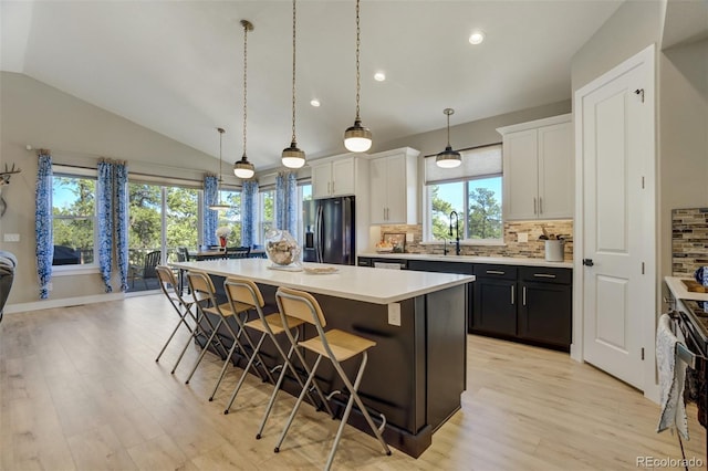 kitchen with a kitchen island, a kitchen bar, light countertops, black appliances, and a sink