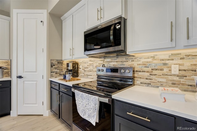 kitchen featuring backsplash, light wood-type flooring, light countertops, white cabinets, and stainless steel appliances