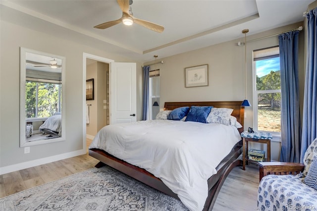 bedroom featuring multiple windows, a tray ceiling, and wood finished floors