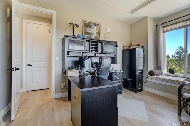 office with baseboards, a healthy amount of sunlight, and light wood-style flooring