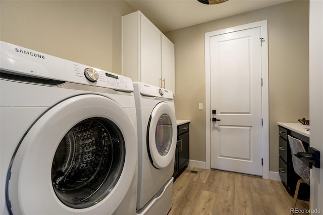 laundry room featuring light wood finished floors, independent washer and dryer, cabinet space, and baseboards