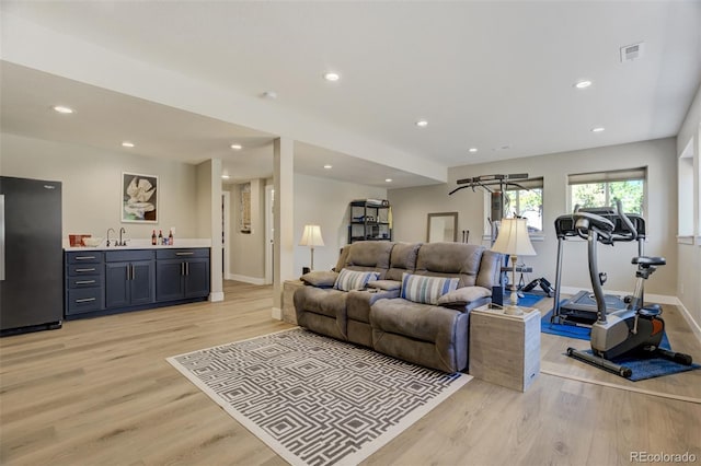 living room featuring indoor wet bar, visible vents, light wood-style flooring, and recessed lighting