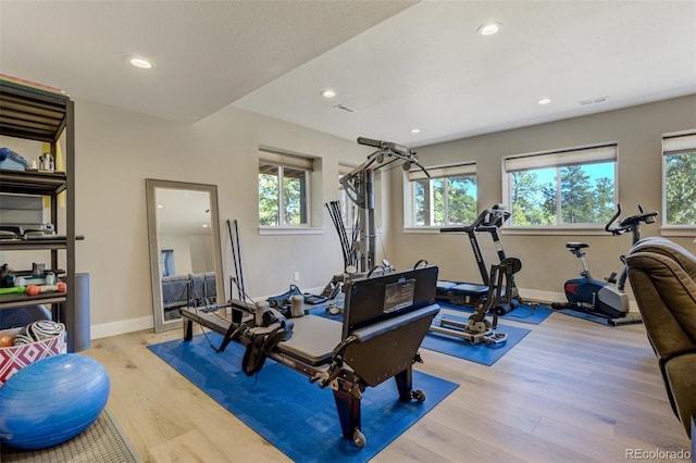 exercise room with a healthy amount of sunlight, light wood-type flooring, and baseboards