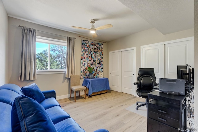 office space with light wood-type flooring, baseboards, and ceiling fan