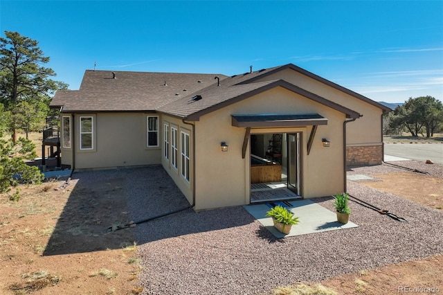 back of property with a patio area, roof with shingles, and stucco siding