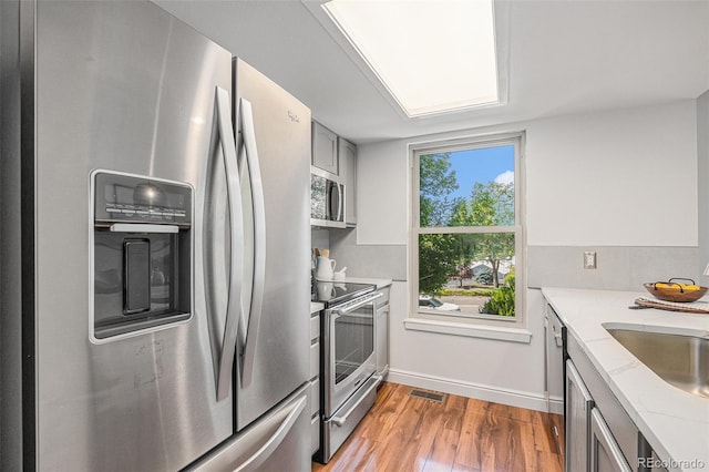 5210 Garrison St Unit 2, Arvada, CO 80002 - kitchen featuring appliances with stainless steel finishes, wood finished floors, light stone countertops, and gray cabinetry