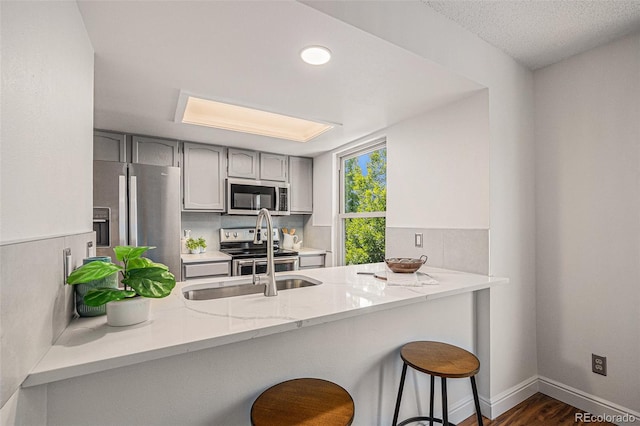 5210 Garrison St Unit 2, Arvada, CO 80002 - kitchen with appliances with stainless steel finishes, a peninsula, gray cabinets, and backsplash