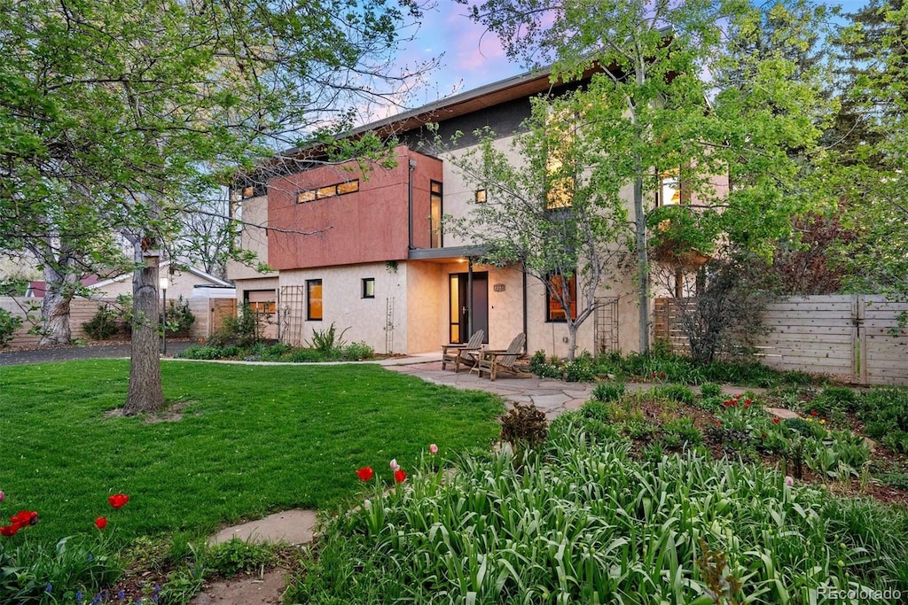 back of property with a patio, a lawn, stucco siding, and fence