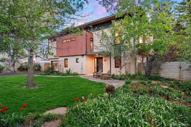 back of property with a patio, a lawn, stucco siding, and fence