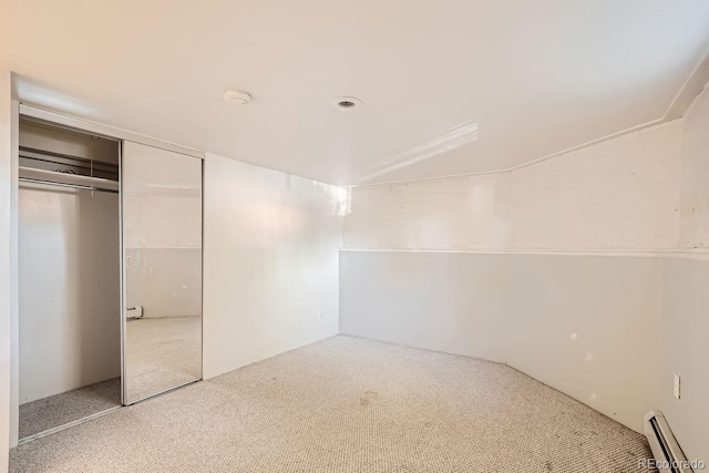 unfurnished bedroom with a closet, a baseboard heating unit, and carpet flooring