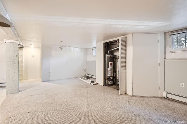 basement featuring light colored carpet, a baseboard radiator, and gas water heater