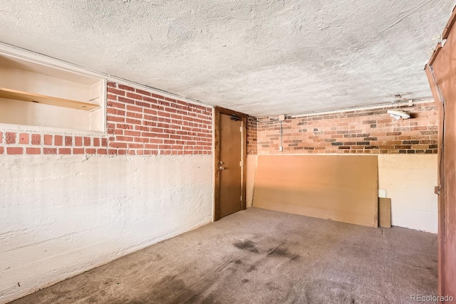 empty room with brick wall, a textured ceiling, and carpet flooring