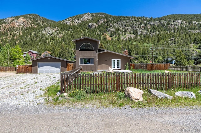 1500 Buckeye Cir, Georgetown, CO 80444 - view of front of property with a detached garage, a forest view, a mountain view, an outdoor structure, and a chimney