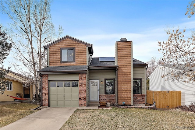 traditional home featuring fence, solar panels, a chimney, concrete driveway, and brick siding