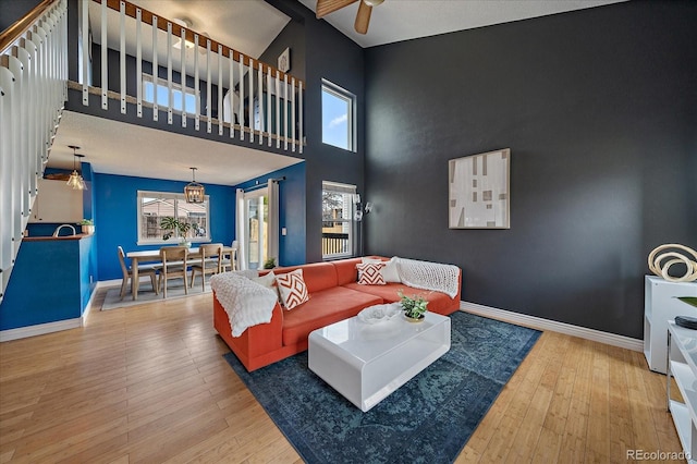 living area featuring an accent wall, a high ceiling, baseboards, and hardwood / wood-style flooring