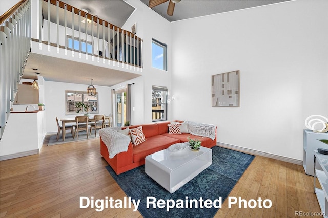 living area featuring a high ceiling, baseboards, and wood-type flooring