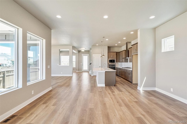 21022 E 63rd Dr, Aurora, CO 80019 - kitchen with wall chimney range hood, sink, appliances with stainless steel finishes, a kitchen island with sink, and decorative light fixtures