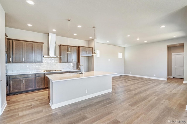 21022 E 63rd Dr, Aurora, CO 80019 - kitchen with wall chimney exhaust hood, sink, decorative light fixtures, stainless steel gas stovetop, and a kitchen island with sink