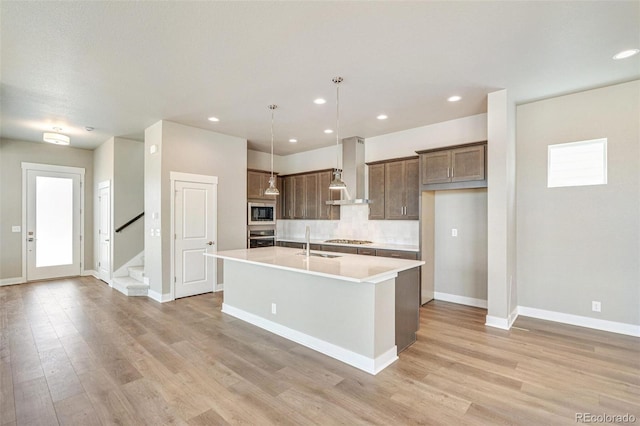 21022 E 63rd Dr, Aurora, CO 80019 - kitchen with pendant lighting, wall chimney range hood, sink, stainless steel appliances, and a center island with sink