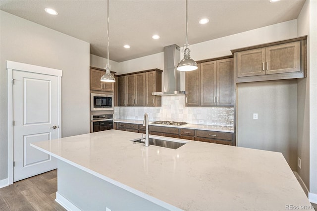 21022 E 63rd Dr, Aurora, CO 80019 - kitchen with appliances with stainless steel finishes, decorative backsplash, hanging light fixtures, light stone counters, and wall chimney exhaust hood