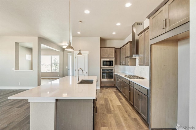 21022 E 63rd Dr, Aurora, CO 80019 - kitchen with appliances with stainless steel finishes, pendant lighting, sink, a kitchen island with sink, and wall chimney range hood