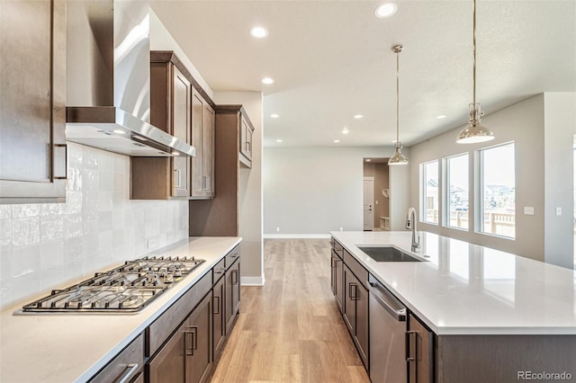21022 E 63rd Dr, Aurora, CO 80019 - kitchen featuring appliances with stainless steel finishes, decorative light fixtures, sink, a kitchen island with sink, and wall chimney exhaust hood