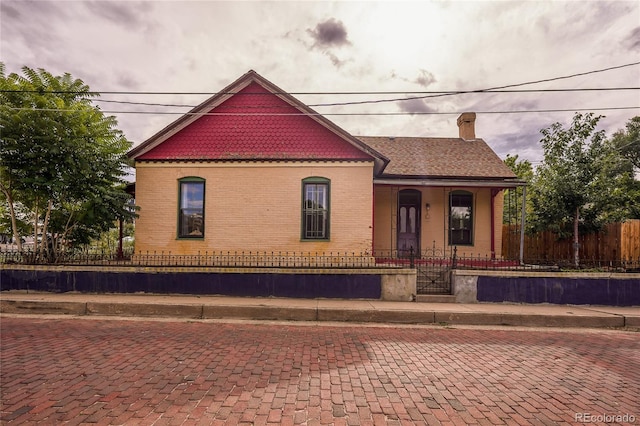 view of front of property featuring a fenced front yard, a chimney, and brick siding