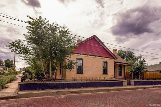 victorian-style house with a fenced front yard and brick siding