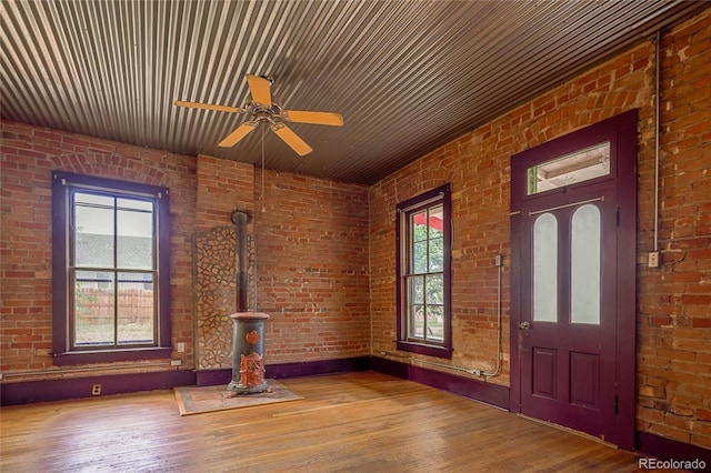 foyer featuring hardwood / wood-style floors, ceiling fan, a wealth of natural light, and brick wall