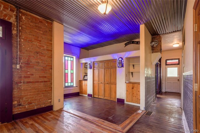 interior space with brick wall and dark hardwood / wood-style floors