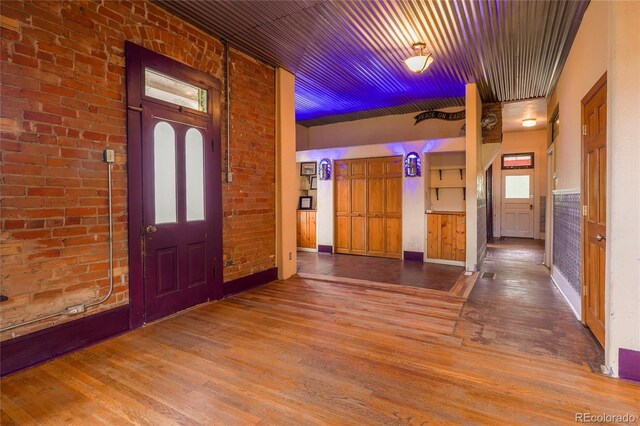 entrance foyer with plenty of natural light, brick wall, and wood-type flooring