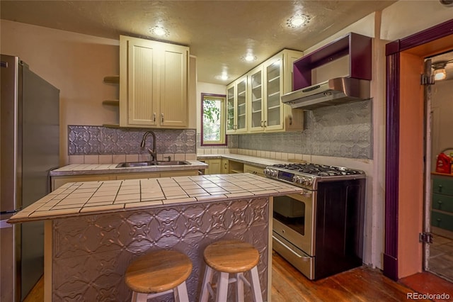 kitchen with a center island, appliances with stainless steel finishes, tile countertops, and sink