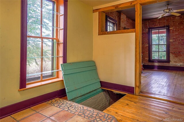 interior space featuring brick wall, ceiling fan, and wood-type flooring