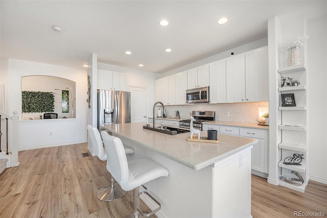 kitchen featuring white cabinetry, light hardwood / wood-style floors, a center island with sink, stainless steel appliances, and sink