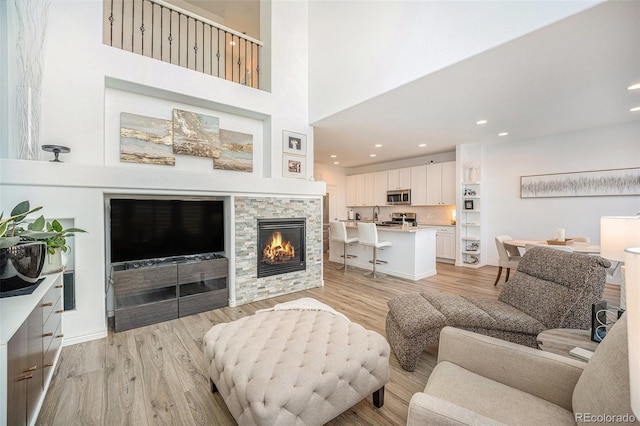 living room featuring a fireplace, a high ceiling, and light wood-type flooring