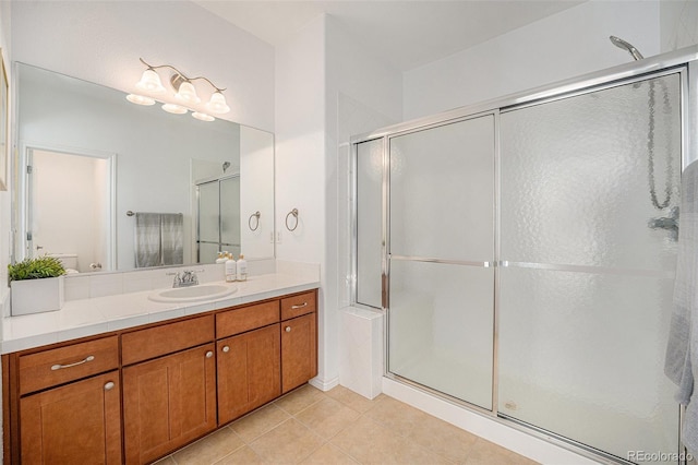 bathroom with walk in shower, vanity, and tile patterned flooring