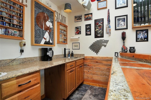 bar featuring light stone counters and sink