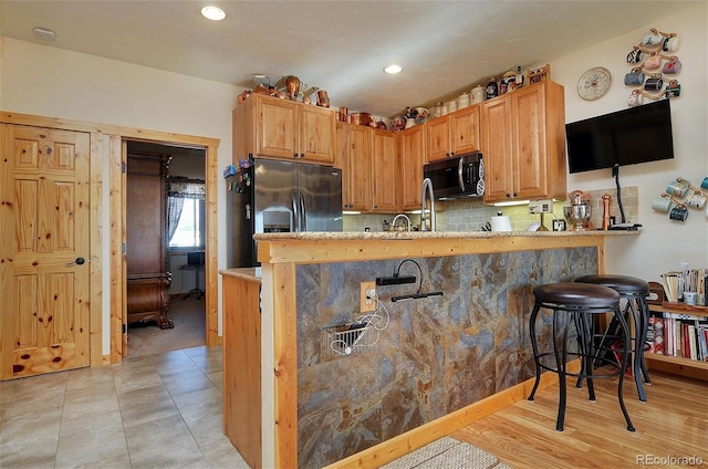 123 Halleys Ave Unit C, Poncha Springs, CO 81242 - kitchen featuring black microwave, a peninsula, light stone counters, stainless steel refrigerator with ice dispenser, and a kitchen bar
