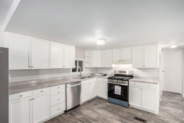 kitchen featuring under cabinet range hood, stainless steel appliances, a sink, visible vents, and open shelves