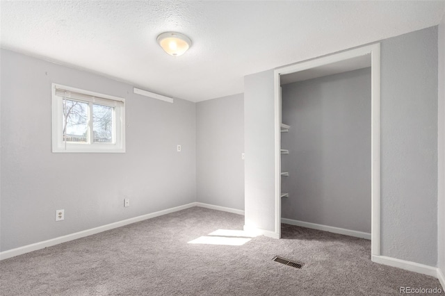 unfurnished bedroom with carpet, a closet, visible vents, a textured ceiling, and baseboards