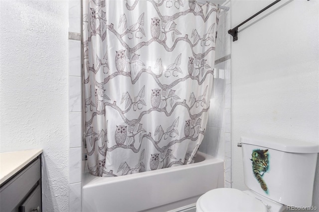 bathroom featuring a textured wall, vanity, shower / bath combo with shower curtain, and toilet