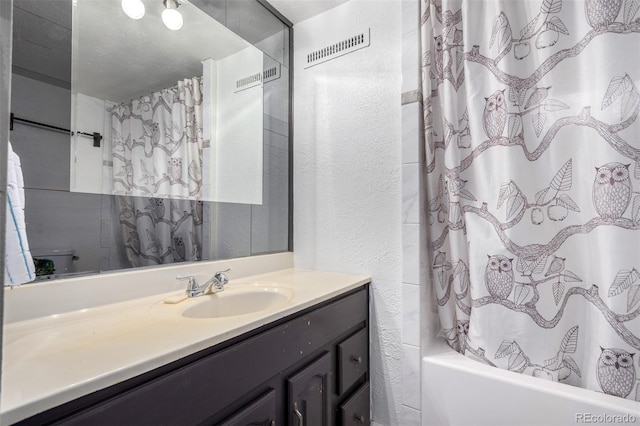 bathroom with a textured wall, shower / bath combo, and vanity