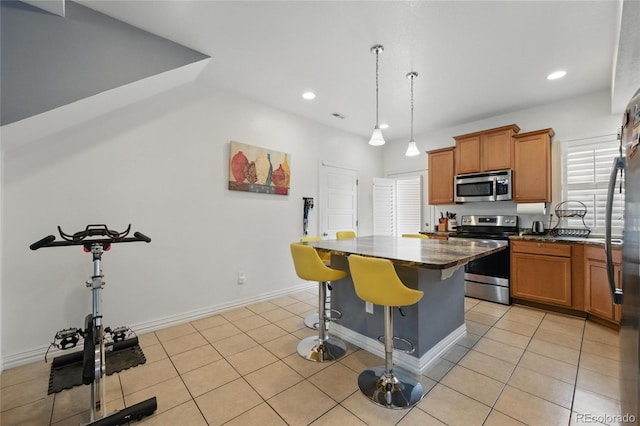18619 E 50th Pl, Denver, CO 80249 - kitchen featuring appliances with stainless steel finishes, a kitchen island, a breakfast bar area, brown cabinets, and recessed lighting