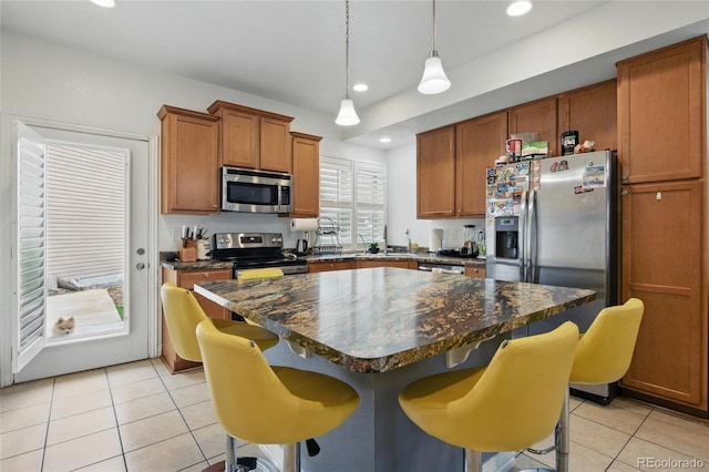 18619 E 50th Pl, Denver, CO 80249 - kitchen with stainless steel appliances, light tile patterned flooring, dark countertops, a kitchen bar, and a center island