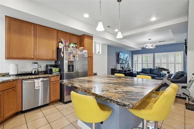 18619 E 50th Pl, Denver, CO 80249 - kitchen featuring stainless steel appliances, light tile patterned floors, open floor plan, a tray ceiling, and brown cabinets