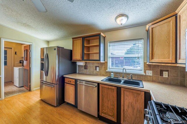 39045 Big Springs Rd, Rush, CO 80833 - kitchen with stainless steel appliances, a sink, washer / dryer, open shelves, and light wood-style flooring